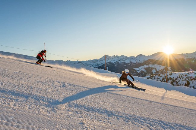 Skifahren auf perfekten Bedingungen und perfekter Kulisse mit der Sonne hinter den Bergen